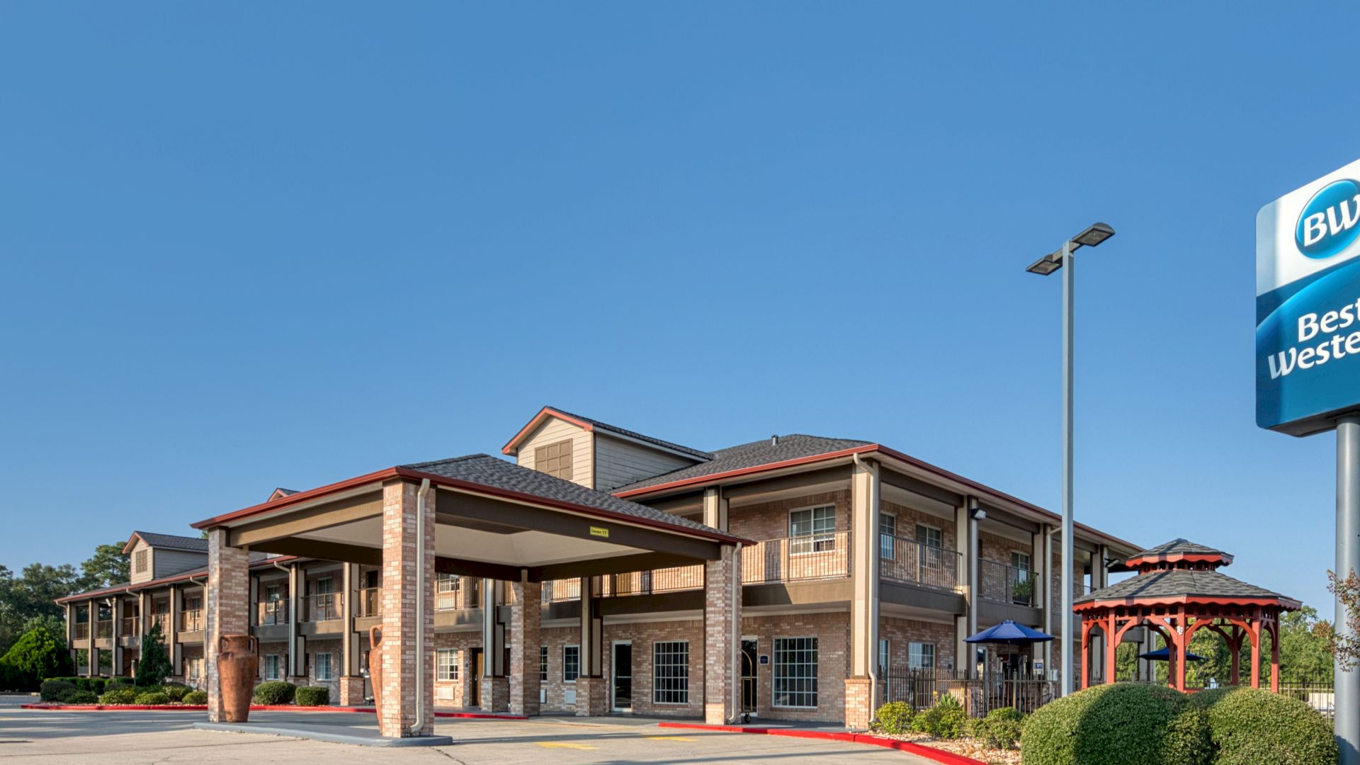 A Best Western hotel exterior with the BW/Best Western sign, blue sky, and covered entrances in view.