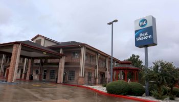 This image shows a Best Western hotel with a sign, a covered entrance, and a gazebo. It appears to be a rainy day.